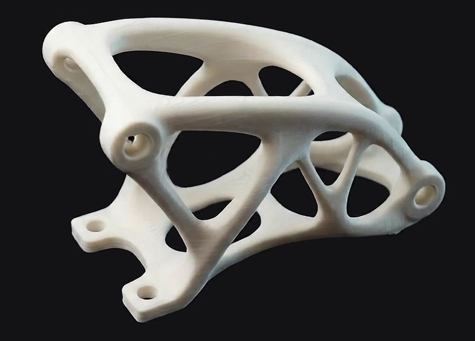 Suport de disseny generatiu imprès en 3D, blanc, amb nervis orgànics com d'os, surant sobre fons fosc.